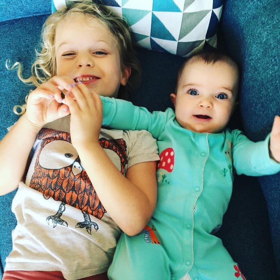 Two young children lying on a sofa, smiling